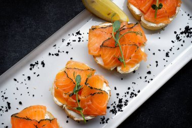 Bruschetta with salmon and butter, on dark background. Banner