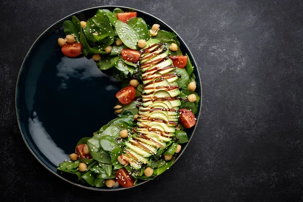 salad with avocado, nuts, tomatoes and sauce. on a dark background
