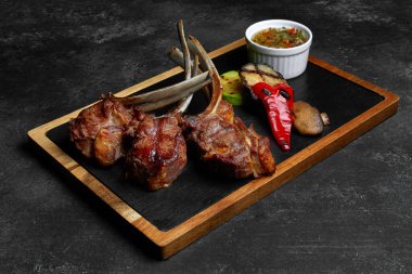 rack of lamb with grilled vegetables and spicy sauce, on a board