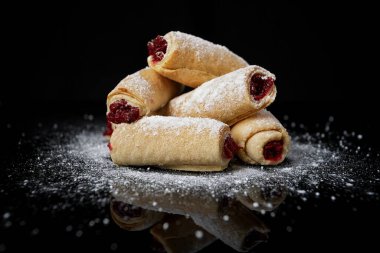 Kiraz reçelli kurabiyeler ve pudra şekerli, siyah aynada yansımalı, yakın plan