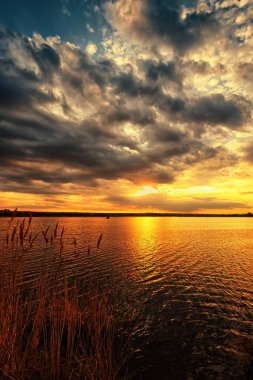 A beautiful lakeside sunset with a dramatic sky and clouds in warm colors