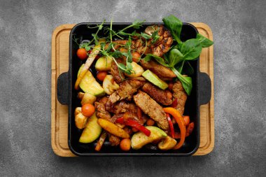 Aromatik dana eti ve siyah tavada kızartılmış sebzeler.