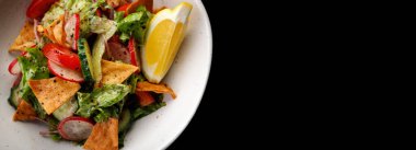 Siyah bir arka planda gevrek cipsli ve taze sebzeli sağlıklı salata.