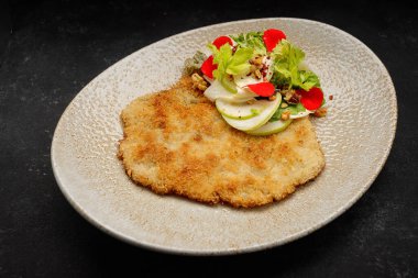 Koyu arkaplanda salatalı biftek.