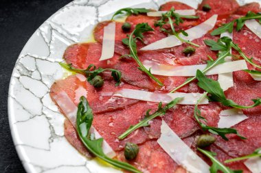 Parmesan peynirli ve roka arkaplanlı et carpaccio.