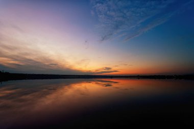 Önünde bulutlar ve su olan güzel bir gün batımı