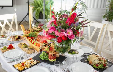 Yemek, çiçek ve sofra takımlarıyla dolu bir ziyafet masası.