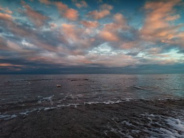 Denizde renkli gün batımı, kırmızı bulutlar, kumlu sahil