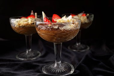 Çilekli çikolatalı tatlı, arka planda siyah cam bir kasede.