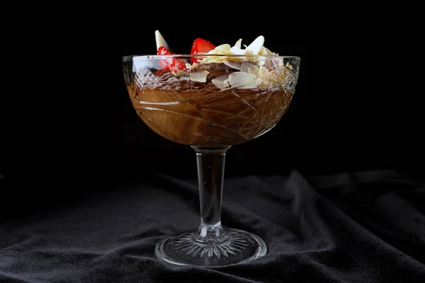 Chocolate dessert with strawberries on a black background in a glass bowl