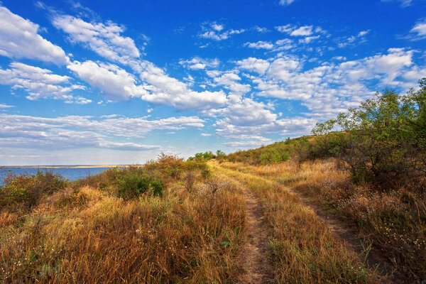 Autumn river bank, blue sky with white clouds, soft evening light
