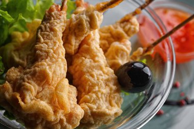 İçinde karanlık bir arka plan üzerinde beyaz bir tabakta tempura karides