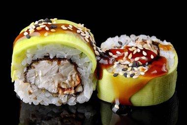 Green dragon sushi roll with eel, avocado and Philadelphia cheese, on a black mirror