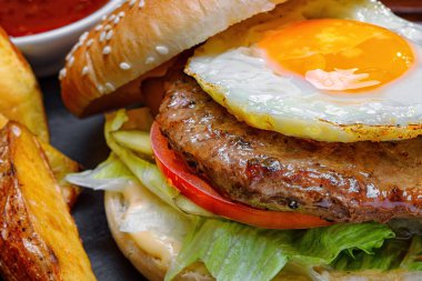 Et ve yumurtalı hamburger, soslu ve patatesli bir pano. Kapat.