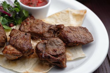 Beyaz bir plaka üzerinde şiş kebap