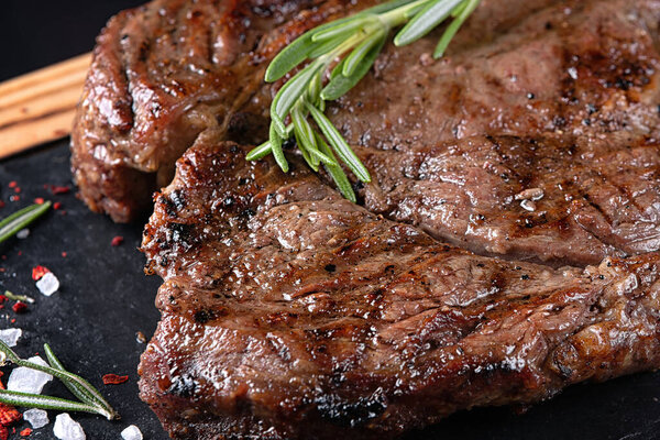 Fried meat steak on slate on a black background. Close up