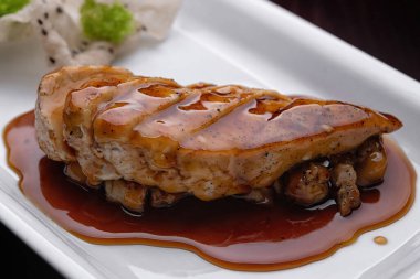 Beyaz tabakta teriyaki soslu tavuk filetosu. Yakın plan.