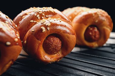 Izgarada hamur içinde pişmiş sosis, koyu bir arka plan.