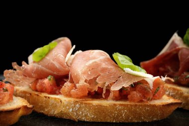 Ağız sulandırıcı, üzerinde tütsülenmiş somon, jambon ve parmesan peyniri olan