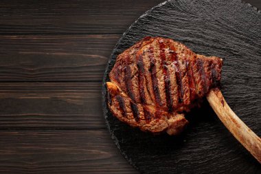 Tomahawk bifteği siyah bir tahtada, ahşap bir arka planda