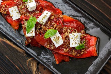 Baked peppers with cheese and spices on a wooden background