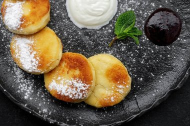 Ekşi krema ve naneli siyah tabakta süzme peynirli kekler.
