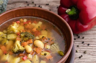 vegetable soup with vegetables and cauliflower in a clay plate, on a wooden surface