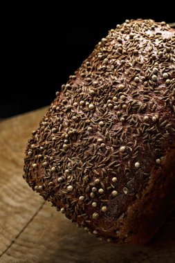Two black loaves of bread on a wooden board on a black background