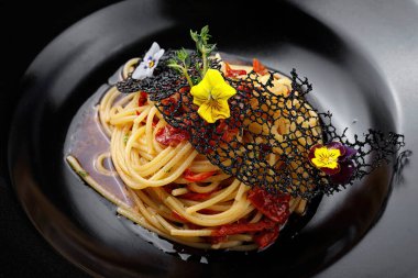 Siyah tabakta kiraz domatesli iştah açıcı spagetti ve ahşap arka plan.