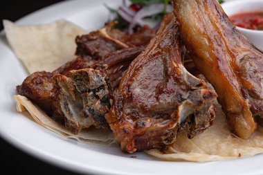 Sos ve soğan ile beyaz bir plaka üzerinde kızarmış kaburga