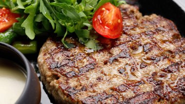 Soslu ızgara domuz eti, roka ve domates.