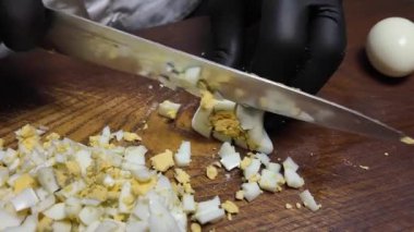 Tahtada bıçakla haşlanmış bir yumurtayı dilimliyor.