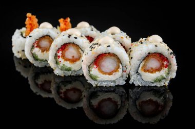 Karides ve krem peynirli suşi rulosu, yansımalı siyah bir aynada.