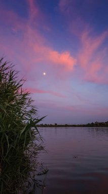 Göl kıyısında gün batımı, suda yansıyan güzel bulutlar.