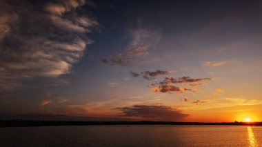 Göl kıyısında gün batımı, suda yansıyan güzel bulutlar.