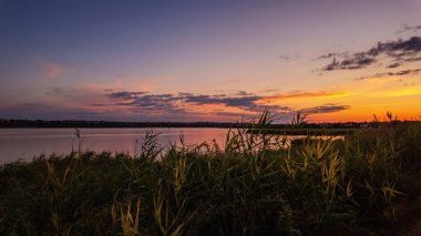Göl kıyısında gün batımı, suda yansıyan güzel bulutlar.