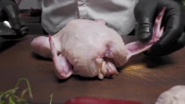 Adam bütün bir tavuğu tahta bir tahtanın üzerinde bıçakla kesiyor.