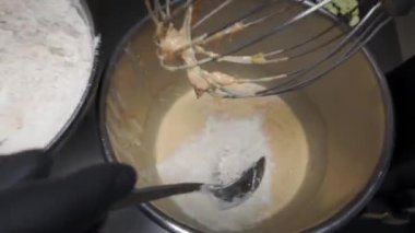 Siyah eldivenli bir adam havuçlu kek hamurunu karıştırıcıda yoğurur..