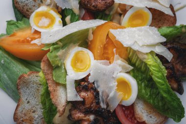 Yumurtalı Sezar salatası, tavuk eti, tabakta kızarmış ekmek.