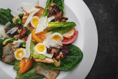 Yumurtalı Sezar salatası, tavuk eti, tabakta kızarmış ekmek.