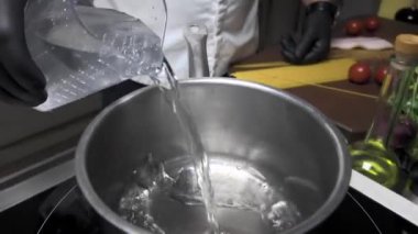 Elektrikli ocakta spagetti pişiren adam.