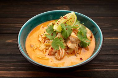 Tahta bir arka planda, deniz mahsullü Tayland Tom Yum çorbası.