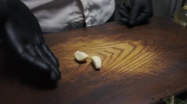 Siyah eldivenli bir aşçı ahşap bir tahtada sarımsak doğruyor..