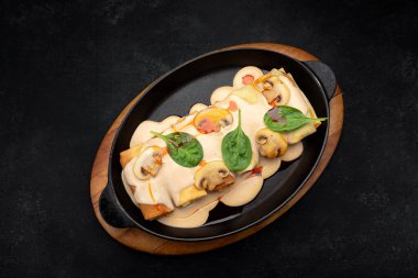 Mantarlı gözleme, sos ve ıspanak, ahşap bir tavada.