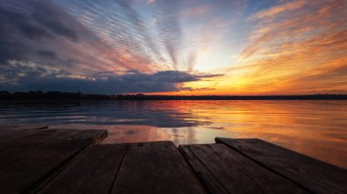 Tüyler şeklinde renkli renkli sirrus bulutlarıyla renkli bir gün batımı. göl