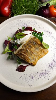 Bitki ve sebzelerle servis edilen kızarmış turna filetosu.