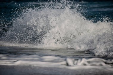 Güçlü okyanus dalgaları kıyıya çarpar ve beyaz deniz köpüğü oluşturur..