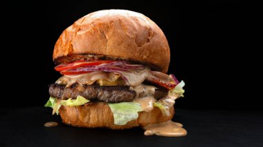 Sulu etli, peynirli ve koyu arkaplanda taze sebzeli lezzetli bir hamburger.