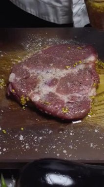 Sıcak tavada etli biftek pişiren bir şefin dikey kısa videosu. Zengin aroma ve mükemmel kavrulmuş kabuk ağız sulandırıcı bir sahne yaratır.