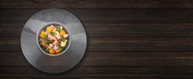 Koyu dokulu bir yüzeyde bir kasede servis edilen taze karides ceviche. Parlak renkler ve turunçgiller.